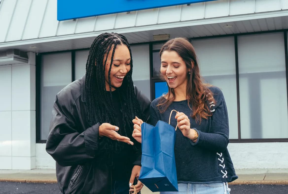 Two friends looking into an Ayr bag together outside an Ayr Cannabis Dispensary