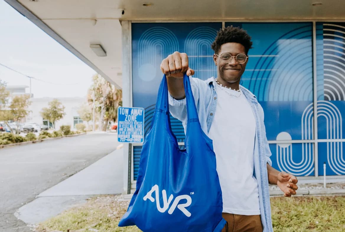 Ayr Dispensaries customer smiling with an Ayr bag outside an Ayr Cannabis Dispensary